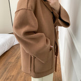 Egyszínű gyapjúkabát hímzéssel, pompongallérral és sállal