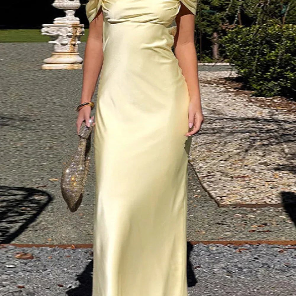 Hosszú, csupasz pántokkal és nyitott háttal ellátott szatén ruha, masnival és vékony pántokkal.